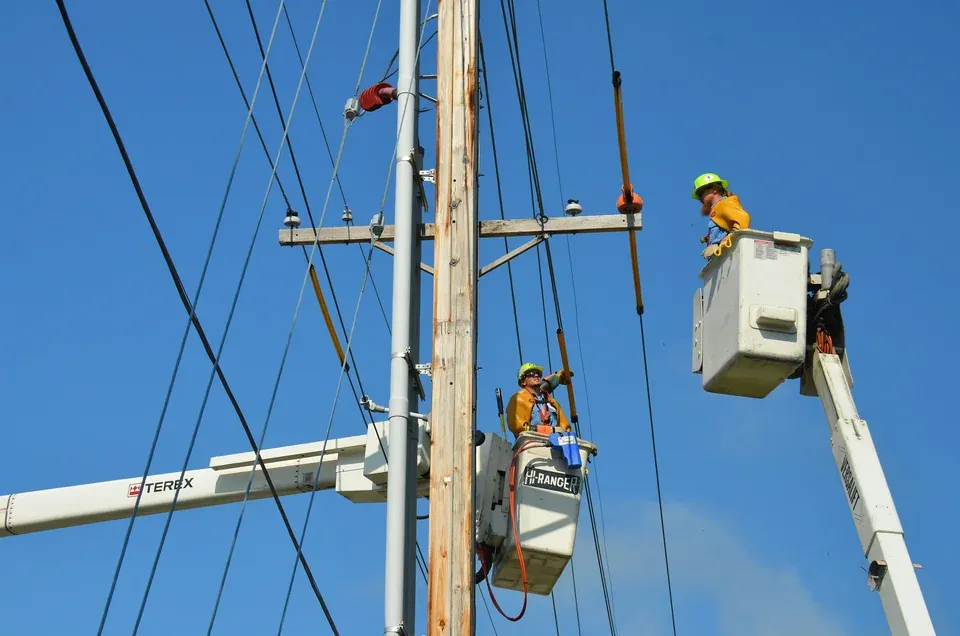 Utility lineworkers in bucket trucks working on overhead power lines